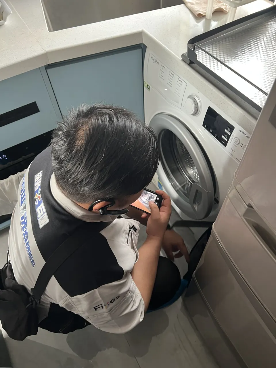 師傅蹲低喺洗衣機門口檢查