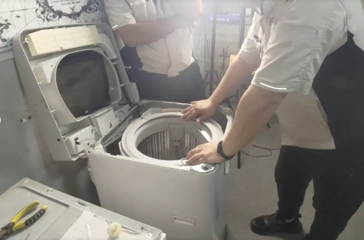 兩位師傅拆開一部頂揭式洗衣機