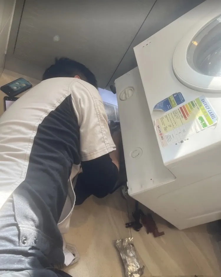 師傅伏低喺洗衣機後面維修